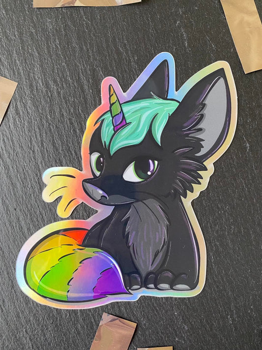 A holographic sticker of a stylized animal character with multicolored accents and a horn, displayed on a slate background.