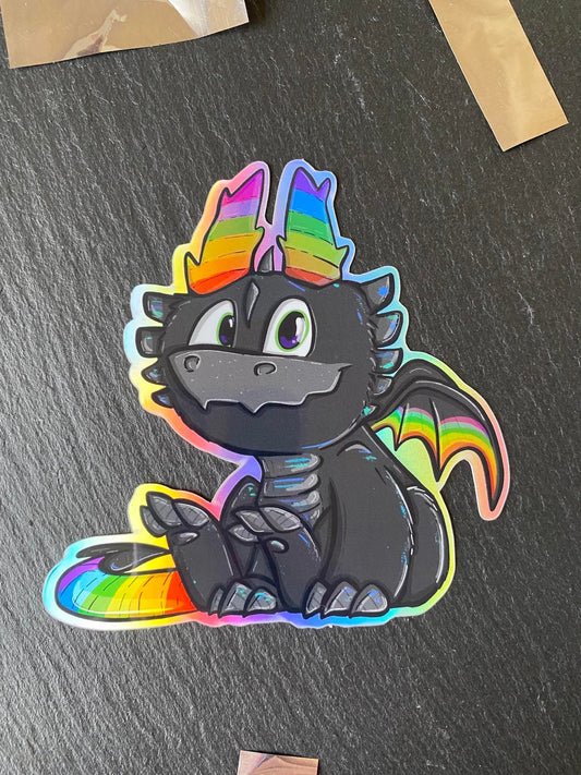 A holographic sticker of a cute dragon with a rainbow-colored tail and black body, sitting and breathing rainbows.